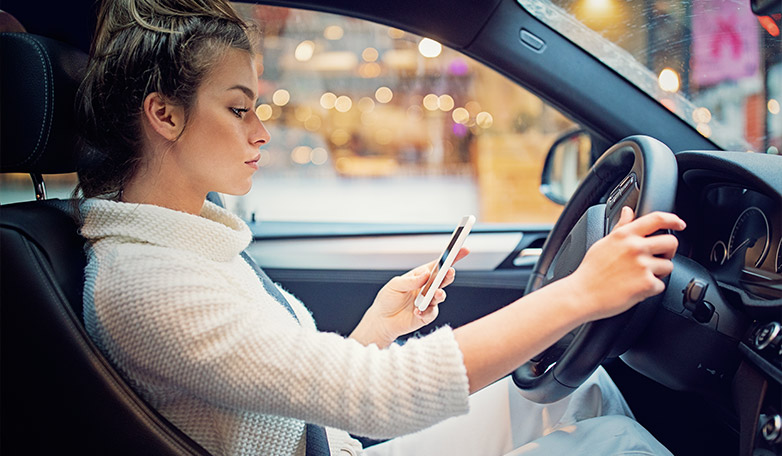 woman driving while distracted checking phone