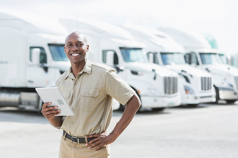 fleet safety manager standing in front of fleet of trucks